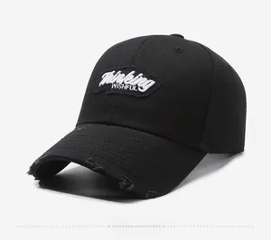 Detail of black baseball cap featuring distressed brim and white letter embroidery