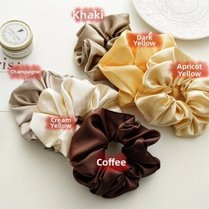 Detailed view of satin scrunchies in khaki, yellow, and champagne with smooth texture