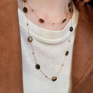 Tiger eye stone long necklace layered on white textured top for an elegant style