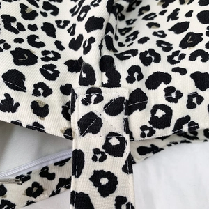 Close-up of reinforced cross-stitch seams on leopard print canvas shoulder bag straps