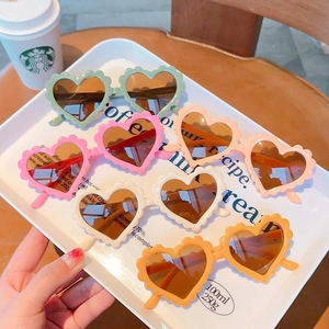 Colorful heart-shaped children sunglasses with scalloped edges displayed on a white tray