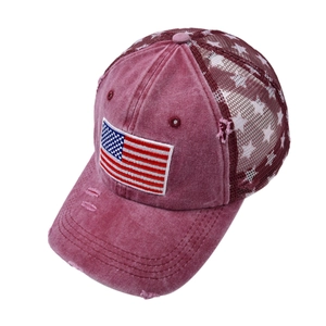 Close-up of distressed wine red trucker hat with American flag patch and star mesh detail