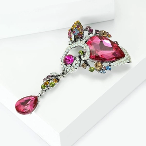 Macro detail of alloy brooch featuring pink droplet rhinestones on a white stand