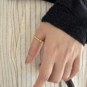 Detailed view of a golden minimalist bamboo-textured ring worn on a person's finger