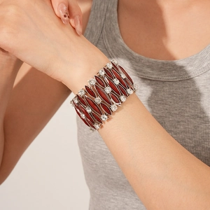 Dettaglio di un ampio bracciale vintage elastico con cristalli rossi e strass bianchi