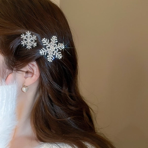 Detail view of two sparkling snowflake hair clips worn on the side of a model's hair