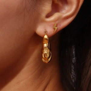 Detailed close-up of 18K gold plated hollow earrings with twisted texture and bolt design