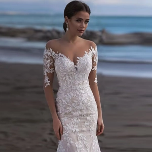 Weißes schulterfreies Hochzeitskleid mit floraler Spitze und langen Ärmeln am Strand
