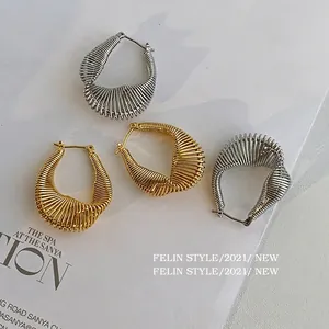 Exaggerated metal twisted hoop earrings in gold and silver with a spiral teardrop design