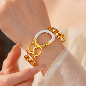 Close-up of gold and white enamel circular link bracelet worn on a woman wrist