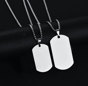 Close-up of two polished stainless steel silver military dog tags on a dark textured background