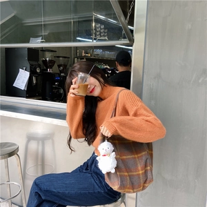 Asian woman in cafe carrying checkered wool tote bag with a cute sheep plush charm.