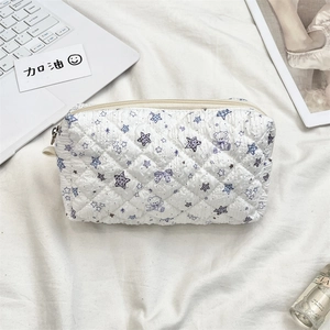 Detailed view of a white quilted cosmetic bag featuring cute purple bear and star patterns