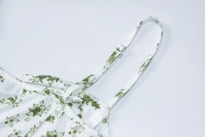 Detalle de la hebilla metálica ajustable en el tirante de un vestido veraniego de flores