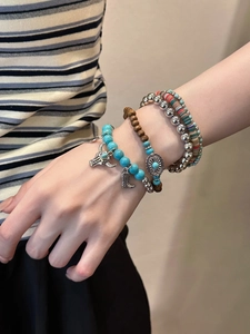 Détail de bracelets bohèmes en perles de bois avec turquoise et breloques au poignet