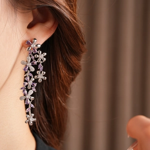 Detail of silver long tassel flower earrings with purple zircons worn by a model