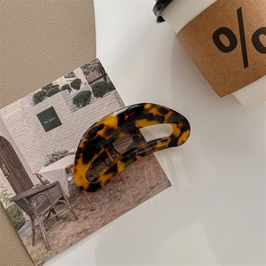 Detail shot of a large tortoiseshell hair claw clip with golden creation France label