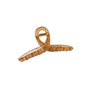 Translucent amber jelly-colored large shark hair claw clip in a minimalist twisted design