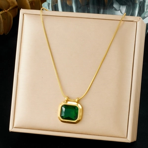 Detail of vintage gold-plated snake chain with emerald green square pendant in beige box