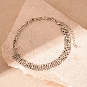 Detail of silver chain choker with rhinestones on light stone background for elegant style