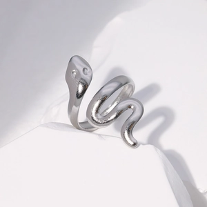 Macro detail of silver snake ring with spiral design on a minimalist stone pedestal