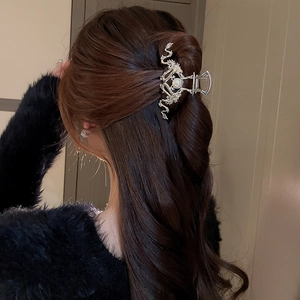 Close-up of a silver dragon hair claw with pearl detail on woman's long dark hair