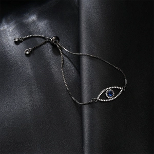 Macro detail of evil eye bracelet with blue zircon inlay on textured black background