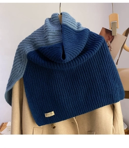 Detail of two-tone knit snood showing thick ribbed texture and brand label on coat