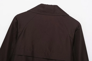 Detailed view of the back collar and storm flap on a dark brown cropped trench coat