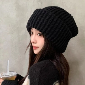 Classic black knitted beanie hat with chunky texture for winter, worn by a model