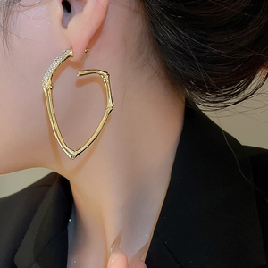 Close-up of gold bamboo-style hoop earring with sparkling rhinestones on model