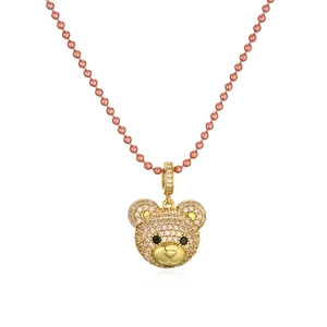 Macro detail of golden bear pendant with pink and white cubic zirconia on a bead chain