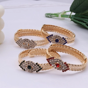 Bracelets dorés torsadés vintage avec charmes d'yeux en cristal colorés sur fond blanc
