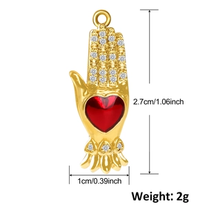 Gold-plated hand-shaped pendant with red heart and crystals on white background