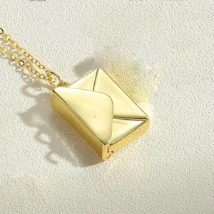 Detailed close-up of golden envelope pendant necklace with polished finish and fine chain