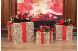Close-up of golden metal wire gift boxes with red bows by a warm fireplace setting