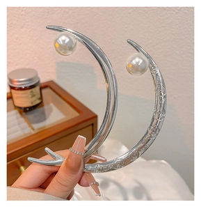 Macro view of silver crescent hair pins with pearl accents and floral engravings