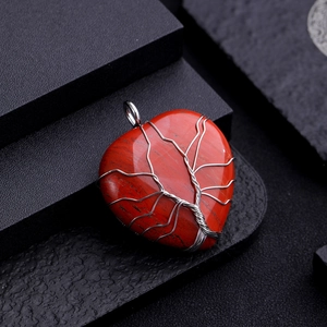 Macro detail of red stone heart pendant with silver wire-wrapped tree of life design