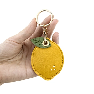 Leather lemon keychain case for Airtag with green leaf detail and gold keyring