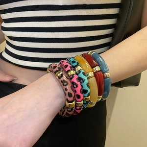 Détail de bracelets géométriques en acrylique multicolore portés au poignet d'un mannequin