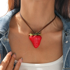 Close-up of realistic red resin strawberry pendant with green leaves on leather necklace