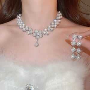 Close-up of elegant flower pearl necklace and rhinestone earrings set worn by a model