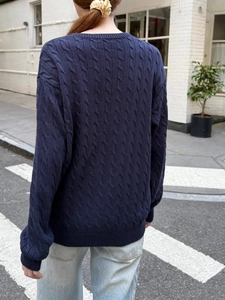 Navy blue cable knit sweater featuring a long sleeve crewneck design for women on city street