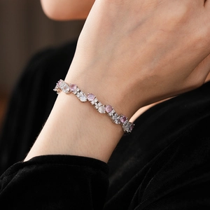Close-up of wavy silver bracelet with pink gemstones and white cubic zirconia on wrist