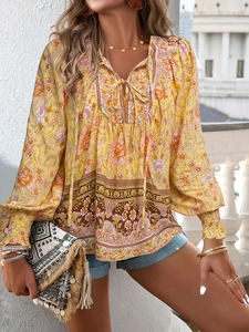 Detail of yellow Bohemian print blouse featuring V-neckline with tassels and tie strings