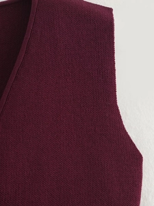 Detailed close-up of wine red knit vest neckline and shoulder stitching texture