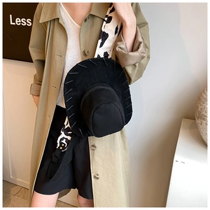 Detail of black cowboy hat shaped crossbody bag with cow print strap on a model