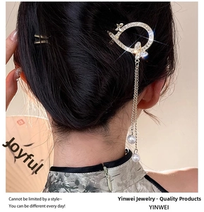 Macro shot of U-shaped gold hair pin with rhinestone butterfly and pearl tassels