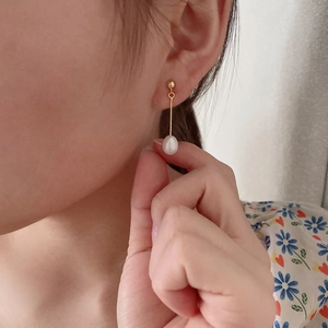 Elegant gold chain earrings with drop freshwater pearls on a model side profile