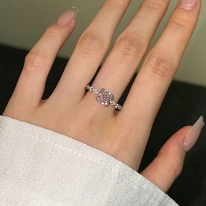 Close-up of a silver ring featuring a princess-cut pink zircon stone and side diamonds